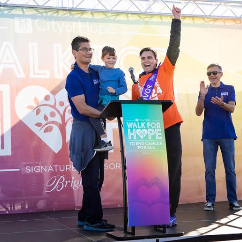two men holding boy smiling standing at podium